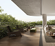 Perspectiva do apartamento garden, com sacada em madeira e mobiliário externo verde.